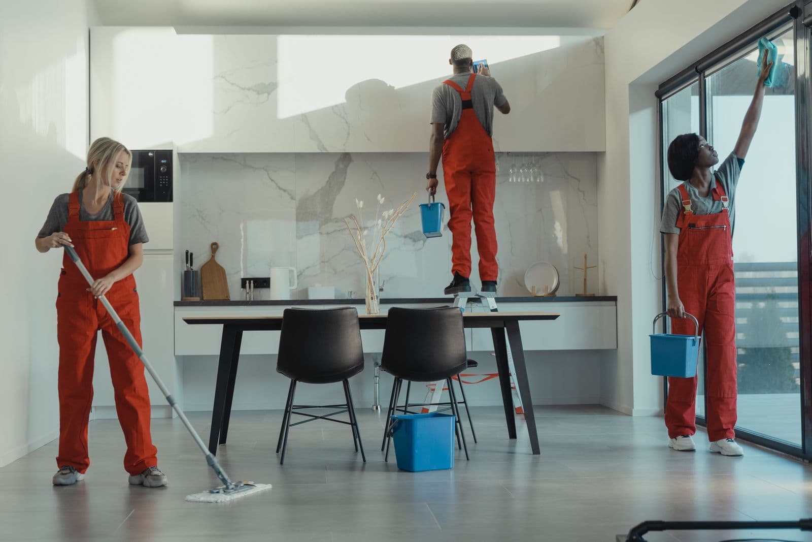 Cleaning team mopping floors and wiping windows in a modern home