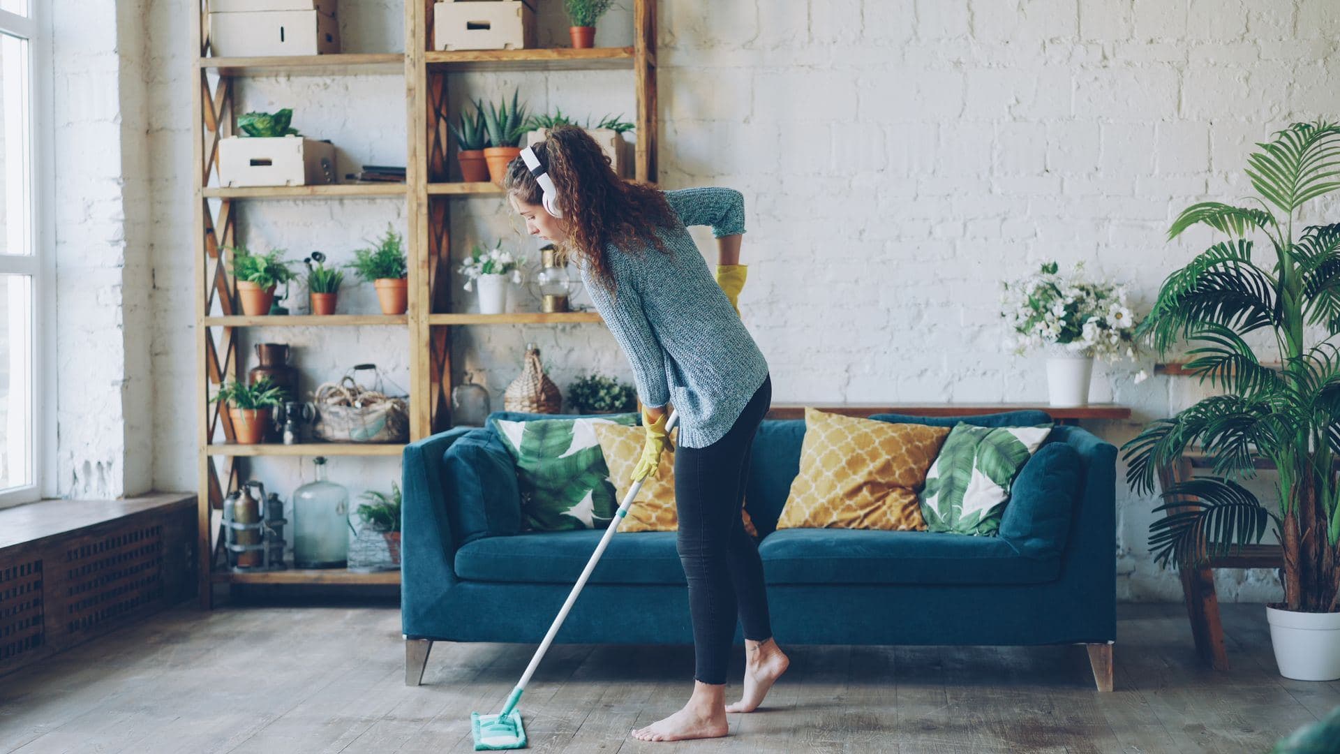 Woman mopping the floor of a bright living room