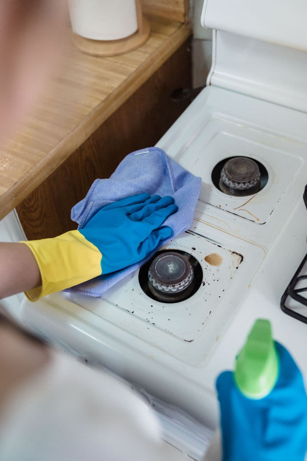 Gloved hand degreasing a kitchen gas stove