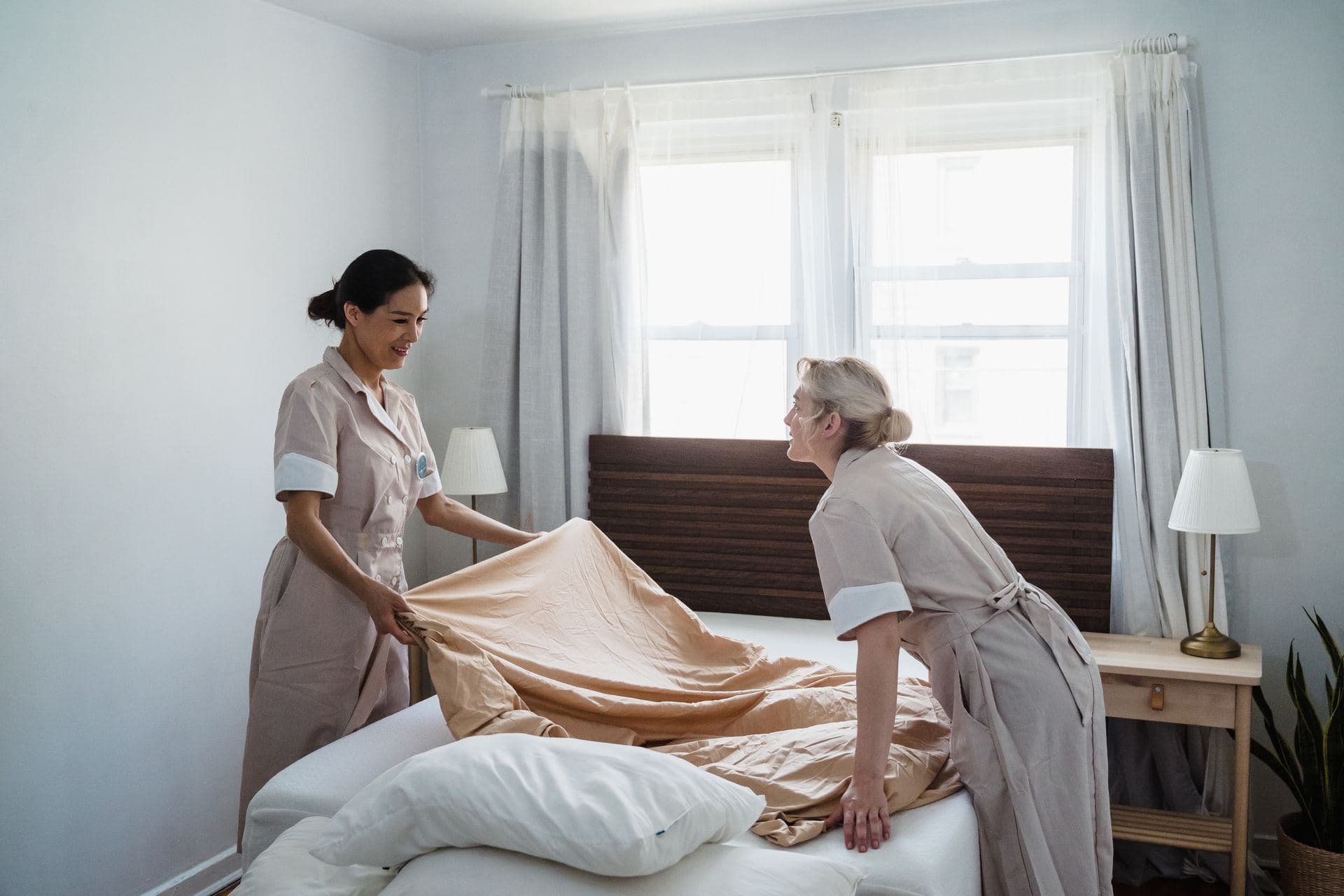 Housekeepers stripping and refreshing a bed and mattress