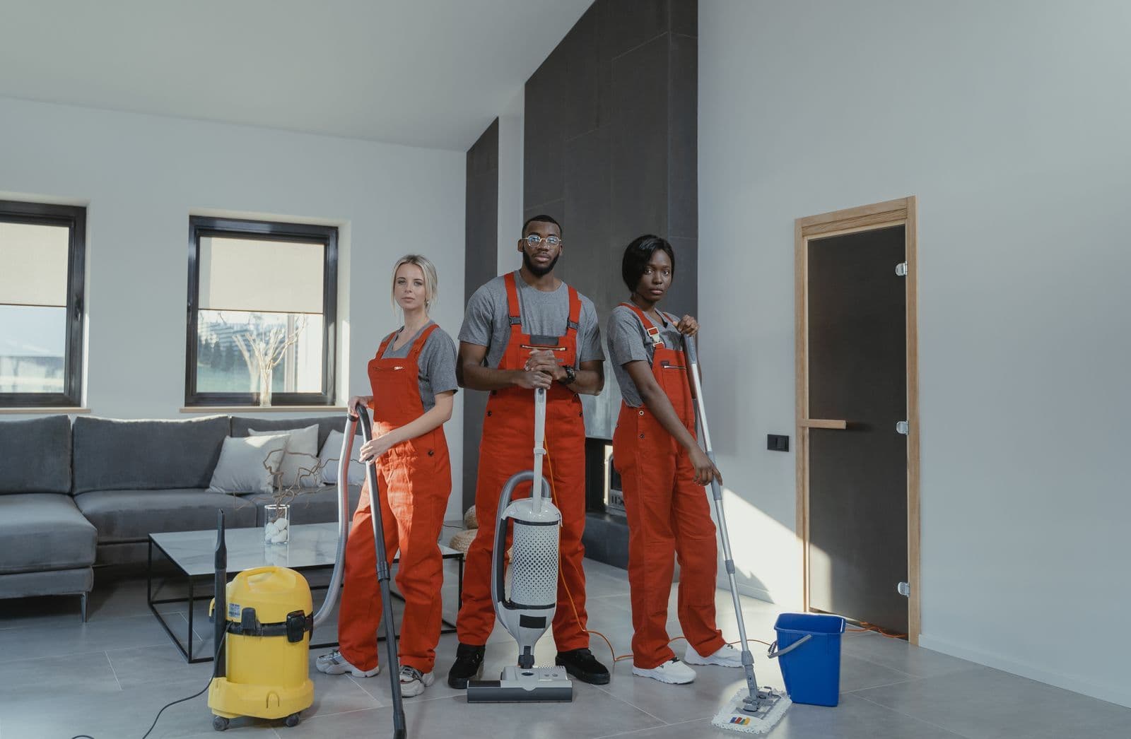 Professional cleaning team with vacuum and extraction machines in a living room