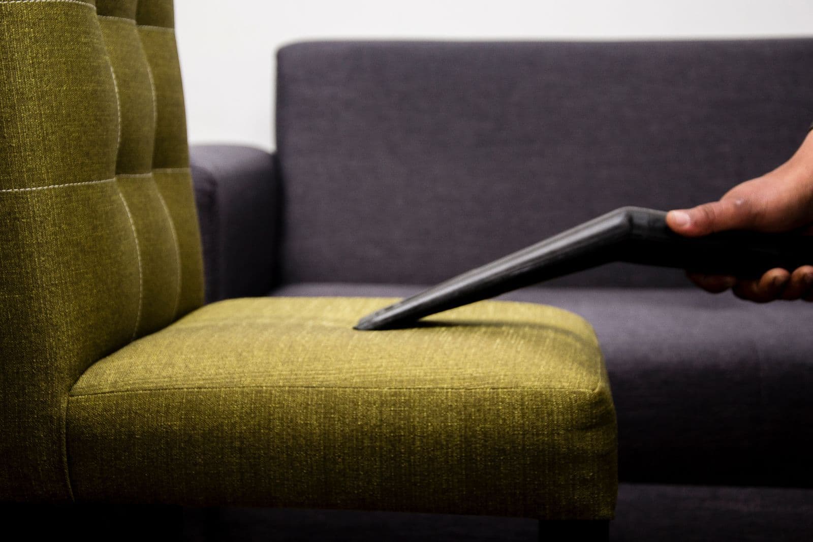 Upholstered armchair seat being cleaned with a vacuum nozzle